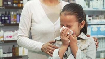 Sick girl sneezes and wipes her nose with a napkin while mother comforts her video