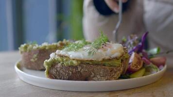 Enjoying a delicious avocado toast with poached egg and salad video