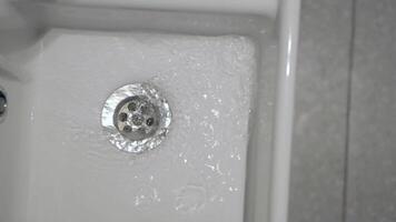 Water flowing down a drain in a bathroom sink during morning routine video