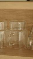 Clear cups displayed on wooden shelf in cozy environment video