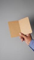 Hand holds brown folder with blank pages in studio setting video