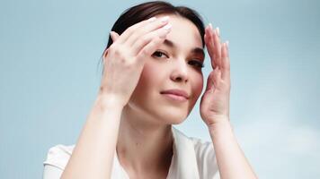 Close-up portrait of happy woman gently touching her face. Her flawless complexion and smooth skin make this image perfect for beauty, makeup, and skincare promotions video