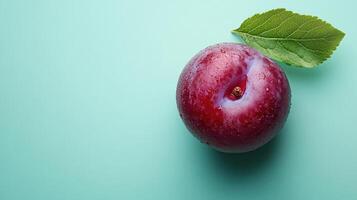 A plump plum resting on a mint green background, creating a vibrant and artistic visual ideal for food-related content, marketing materials, or culinary blogs. photo