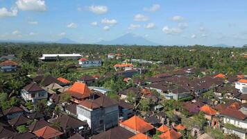 Aerial view of Ubud village with traditional rooftops, tropical jungle, and volcano visible on the horizon in Bali, Indonesia. video