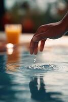 Close-up shot of a hand gently touching the surface of calm water, creating circular ripples and sparkling droplets. photo