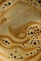 Dark coffee bubbles on velvety crema, swirls and textures forming an abstract pattern photo