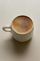 Close up of a cappuccino in a matte light ceramic cup with an irregular rim. photo