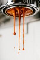 An ultra-detailed close-up of espresso being extracted from a professional portafilter. Multiple silky coffee streams flow smoothly downward, forming rich brown drops filled with crema. photo