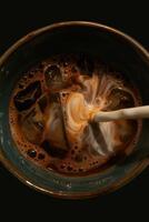 Top down view of an iced coffee cup with freshly added cream. Ice cubes, dark foam around the edges, white creamy swirl creating a beautiful vortex. photo