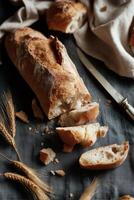 A rustic still life of freshly baked artisan bread, partially sliced on a dark textured surface. photo
