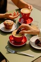 A cozy and vibrant outdoor cafe scene showing two people enjoying coffee and pastries at a green table. photo