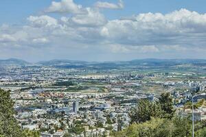 Expansive aerial view of a cityscape with industrial zones, buildings, and greenery under a sky dotted with large clouds photo
