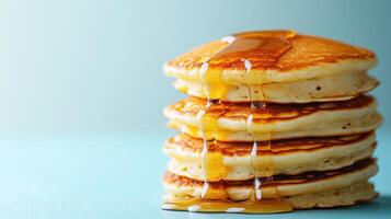 Delicious Stack of Fluffy Pancakes Drenched in Maple Syrup Set Against a Light Blue Background, Perfect for Breakfast Promotions and Food Blogs photo