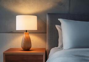 A wooden lamp sits on a nightstand next to a bed photo