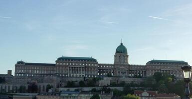 Panoramic view of Buda Castle in Budapest, Hungary, with green dome and historic architecture on hilltop, surrounded by stone walls and greenery photo