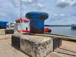 Mooring bollard with rope to tie the ship when docked in the harbor photo