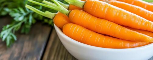 Fresh carrots in a white bowl on a wooden table. photo