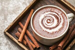 Warm cup of cocoa with cinnamon sticks in a rustic wooden tray. photo