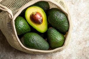 Avocados in a mesh bag on a textured surface. photo