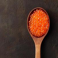 Wooden spoon filled with vibrant orange fish roe on a textured surface. photo