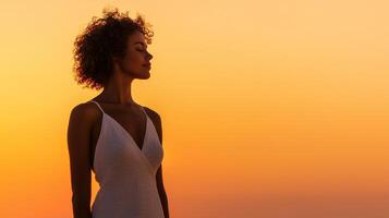Serene woman gazing at a sunset with curly hair and elegant attire. photo
