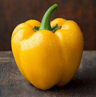 Fresh yellow bell pepper with water droplets on wooden background. photo