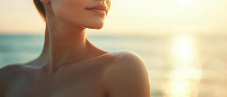 Woman with sunlit skin by the ocean at sunset. photo