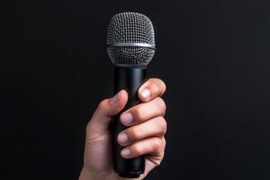 Microphone held in hand against a dark background. Communication skills persuasion. photo