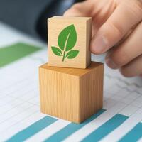 Hand placing a wooden block with a leaf symbol on a chart. photo