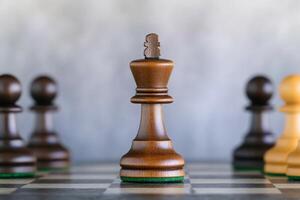 Chess pieces with a focus on the king, set on a textured board. photo