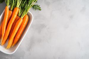 Fresh carrots arranged in a bowl on a textured surface. photo