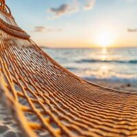 Hammock by the sea at sunset with soft waves in the background. photo