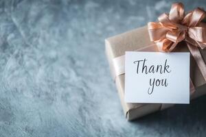 Gift box with a thank you card on a textured surface. photo