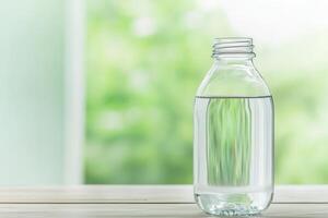 Clear glass water bottle on a wooden surface with a blurred background. photo