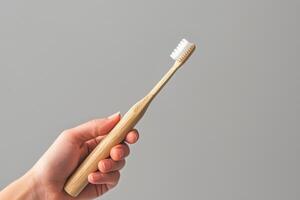 Hand holding a toothbrush against a plain background. photo