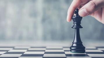 A hand moving a black king chess piece on a checkered board. photo