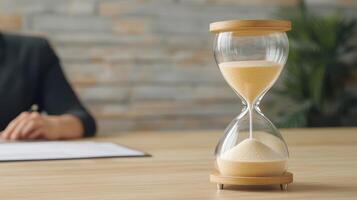 Hourglass on a table with a blurred figure in the background. photo