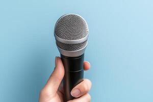 Hand holding a microphone against a blue background. Communication skills persuasion. photo