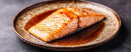 Fresh salmon fillet on a textured plate with sauce. photo