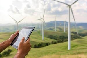 Person using a tablet with wind turbines in the background. photo