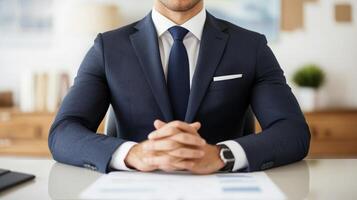 Business professional sitting with hands clasped at a desk. photo