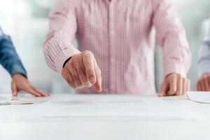 Hands pointing at documents on a table in a collaborative setting. photo