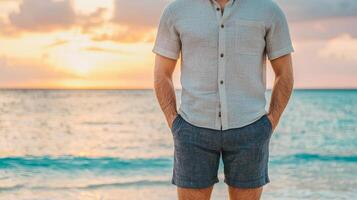 Man standing on the beach at sunset, wearing casual summer attire. photo