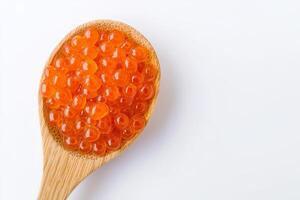 Spoonful of vibrant orange fish roe on a wooden spoon against a white background. photo