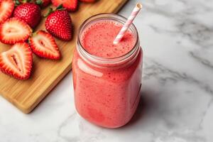 Fresh strawberry smoothie in a jar with a straw and sliced berries. photo