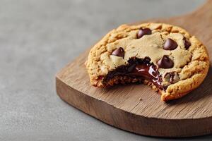 Delicious chocolate chip cookie on a wooden board, partially bitten. photo