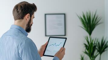 Man analyzing business data on a tablet in a modern office environment. photo
