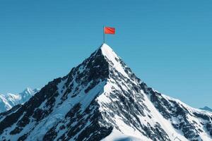 Snow-capped mountain peak with a red flag waving at the summit. photo