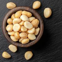 Bowl of seeds on a dark surface, some scattered around. photo