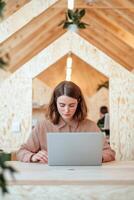 A person working on a laptop in a modern wooden workspace. Inclusive business social enterprise. photo
